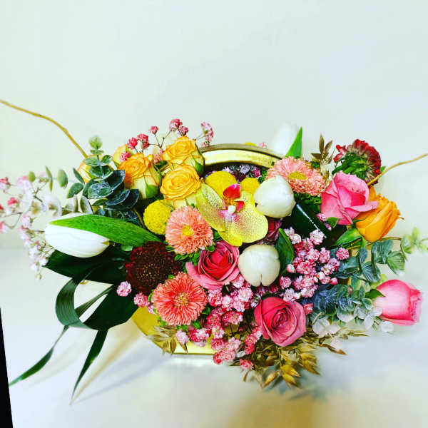 Mixed bouquet with roses, orchids, and daisies in a gold container