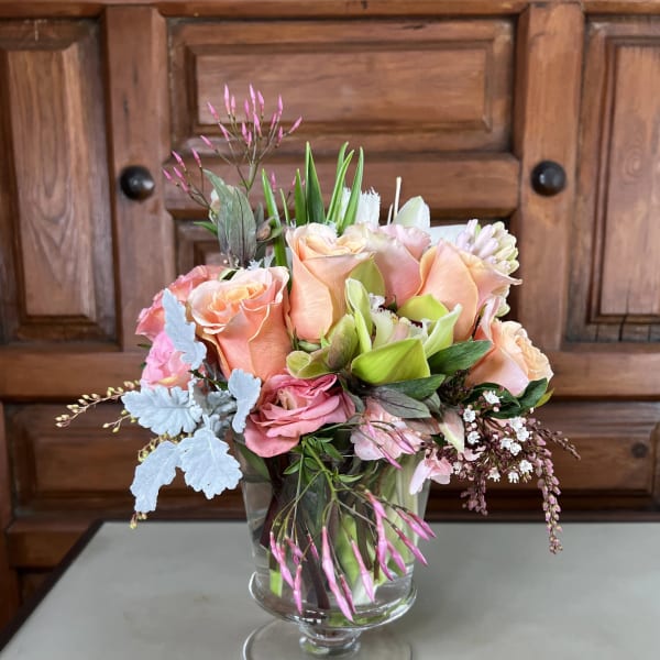 Peach and pink roses arranged in a clear glass vase