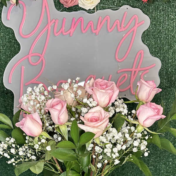 Pink roses and baby's breath in a clear vase with a pink ribbon