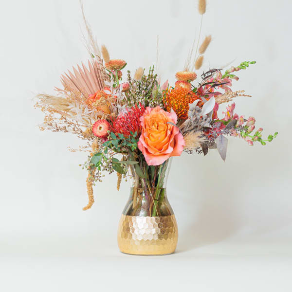 Mixed bouquet in a gold vase with orange and pink blooms