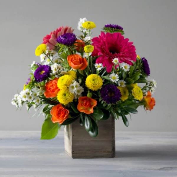 Mixed bouquet of orange roses, pink gerberas, and yellow and purple mums in a wooden box