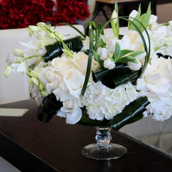 White roses and orchids arranged in a clear glass vase