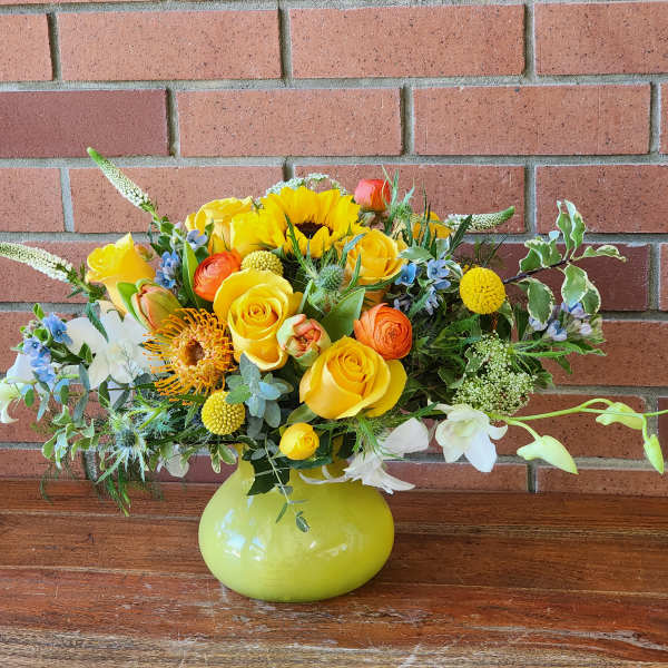 Bright mixed bouquet in a lime-green vase with yellow and orange flowers
