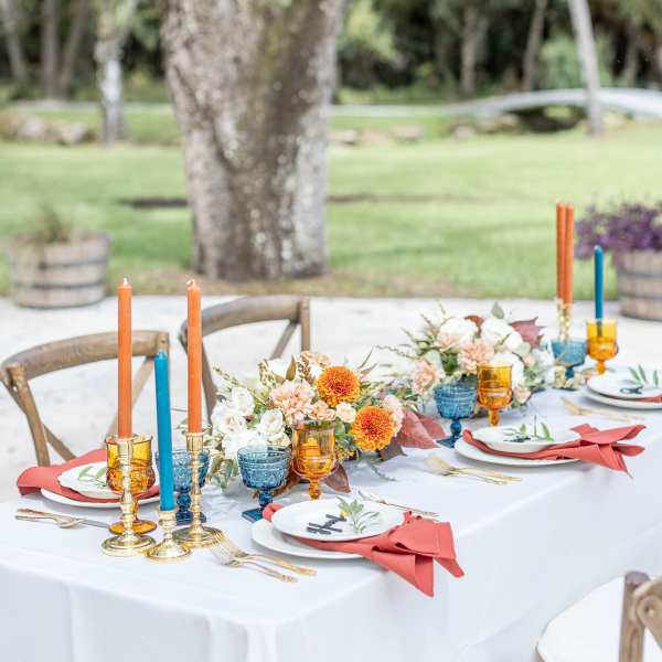 Outdoor table set with floral centerpieces and colorful candles