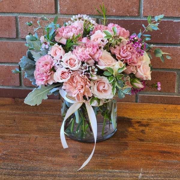 Pink and blush bouquet in a glass vase with a white ribbon