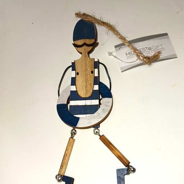 Wooden sailor ornament with blue and white details and a hanging twine loop