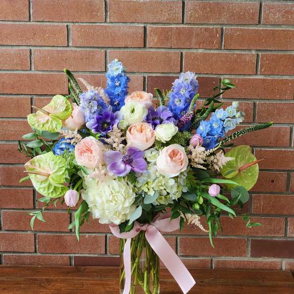 Pastel bouquet in a clear glass vase with pink, purple, and blue blooms