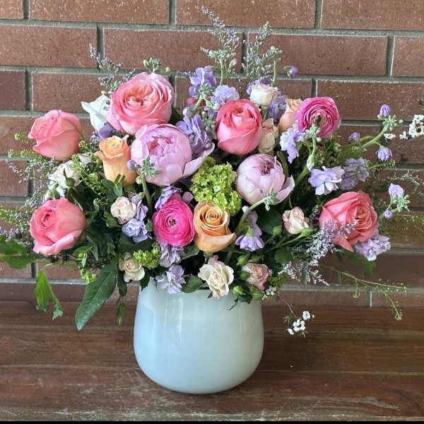 Pink and lavender flower arrangement in a pale blue vase