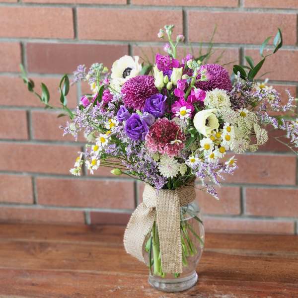 Mixed bouquet of purple, white, and pink flowers in a glass vase