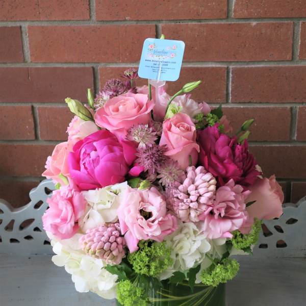 Pink and white flower arrangement with roses, peonies and hydrangeas in a glass vase with leaf wrap