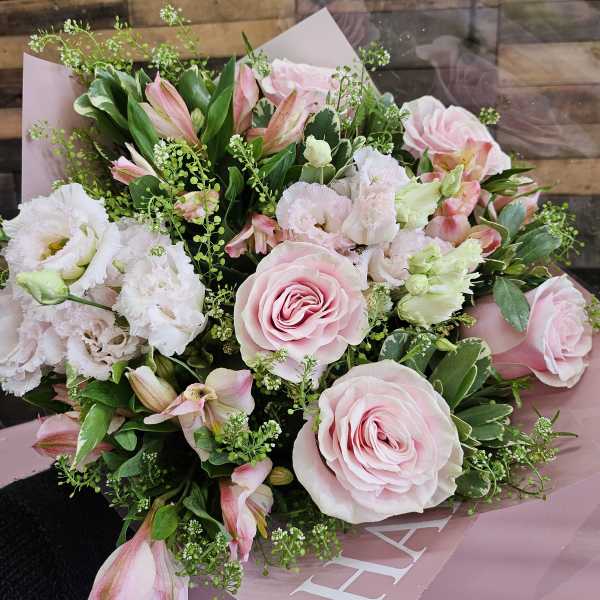 Pink roses and white blooms in a hand-tied bouquet with pink wrap