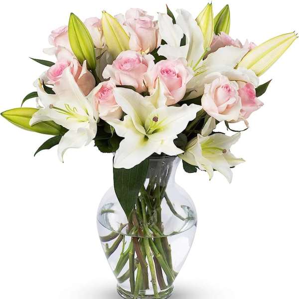 Pink roses and white lilies arranged in a clear glass vase