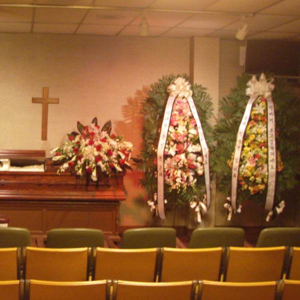 Funeral chapel with casket sprays and standing floral wreaths around a casket