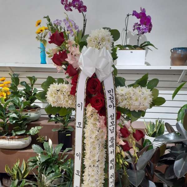 Tall standing floral wreath with red roses, white chrysanthemums, and orchids