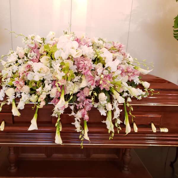 Large pastel floral spray on a casket with white and pink blooms