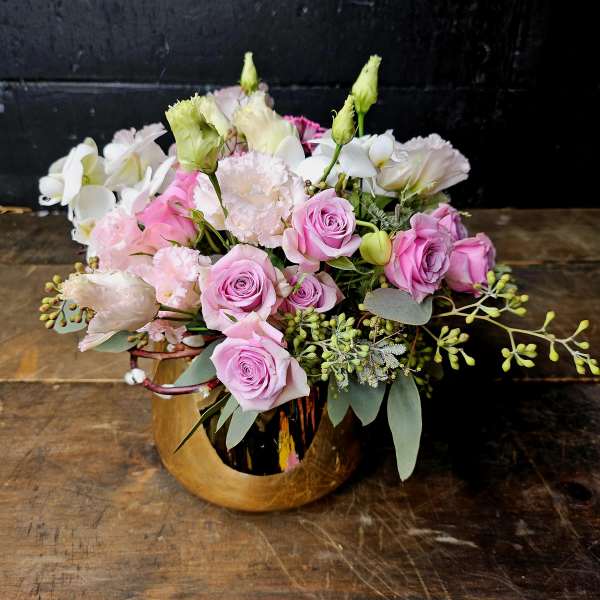 Pink roses and white blooms arranged in a gold vase