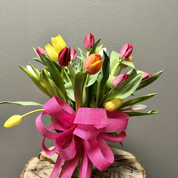 Bouquet of multicolored tulips tied with a bright pink ribbon