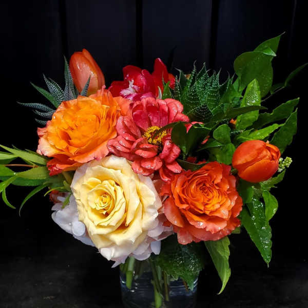 Colorful bouquet of roses and tulips in a clear glass vase