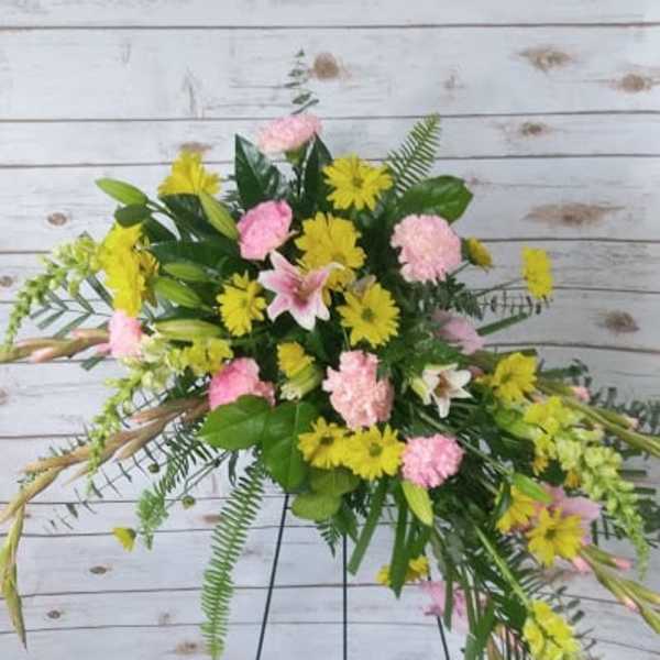 Standing floral spray with pink and yellow flowers on a wire easel