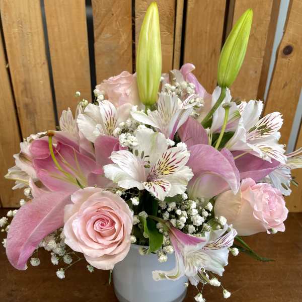 Pink roses and lilies arranged in a white vase