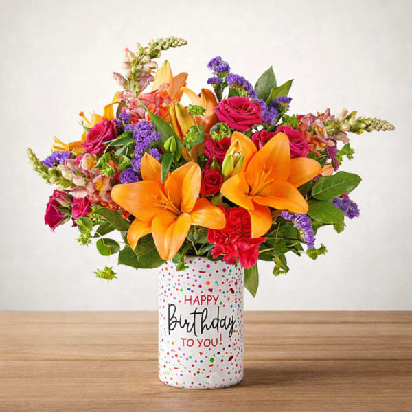 Bright mixed bouquet with orange lilies and pink roses in a birthday vase