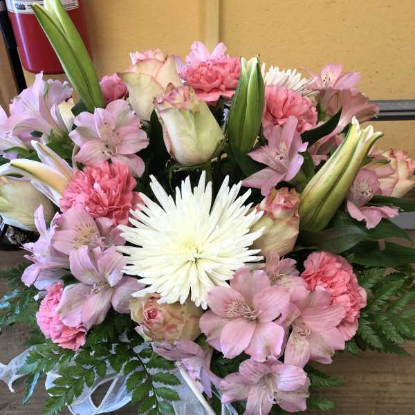 Pink and white mixed bouquet with lilies, roses, carnations, and a white ribbon