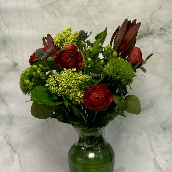 Red and green floral arrangement in a glass vase