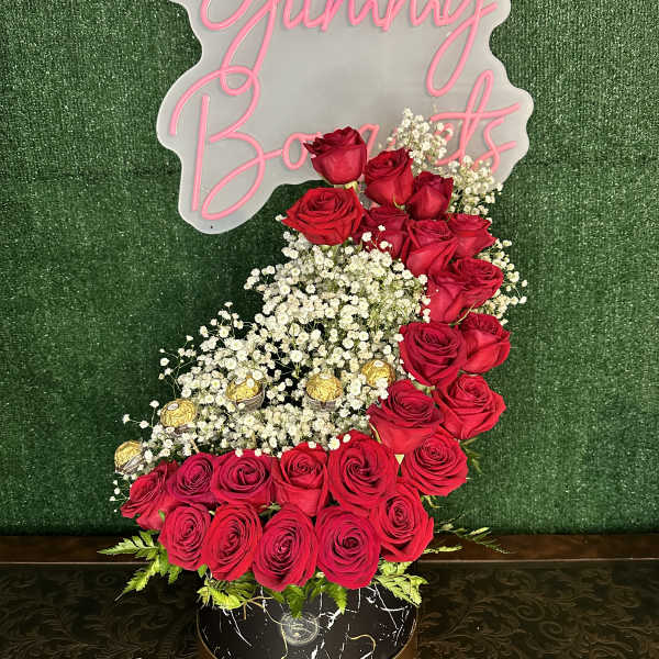 Red roses and baby's breath arranged around a "Yummy Bites" sign