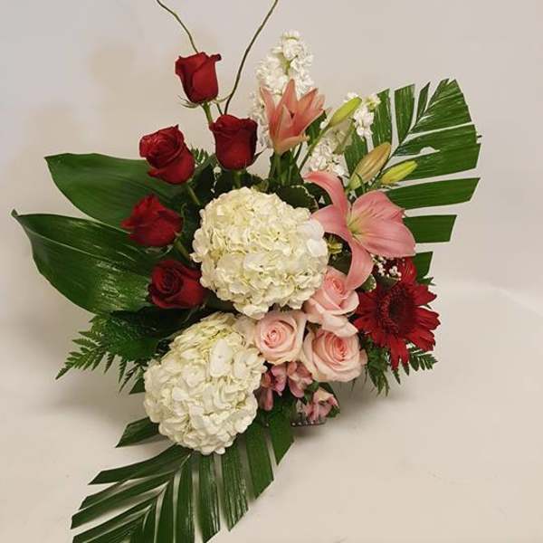 Floral arrangement with red roses, pink lilies, and white hydrangeas