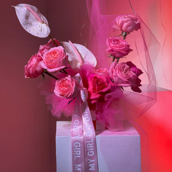 Pink rose arrangement with white anthuriums and a ribbon on a pedestal