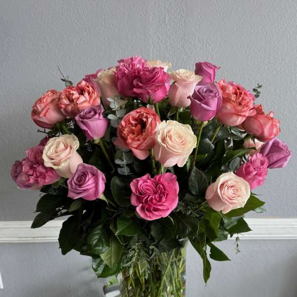 Pink and lavender roses arranged in a clear glass vase