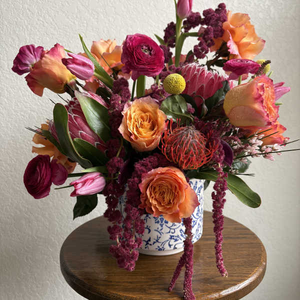 Colorful bouquet of orange and magenta flowers in a blue-and-white vase