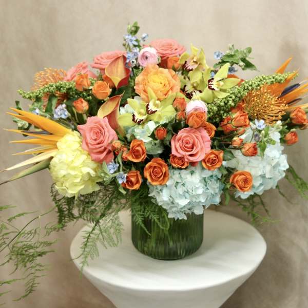 Colorful mixed bouquet in a green glass vase with roses and hydrangeas