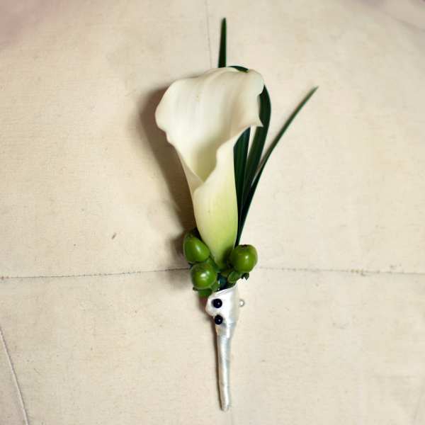 White calla lily boutonniere with green berries and ribbon wrap