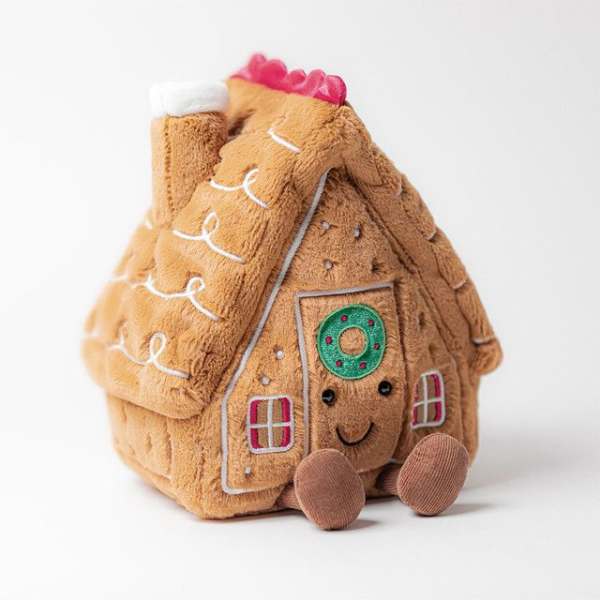 Plush gingerbread house toy with a smiling face and pink roof detail