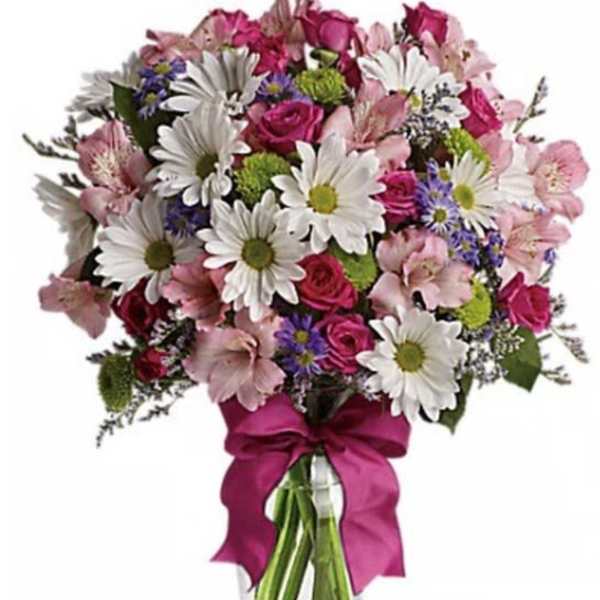 Bouquet of pink roses and white daisies in a clear glass vase with a magenta ribbon