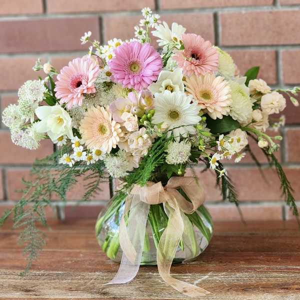 Pastel mixed bouquet in a round glass vase with a ribbon
