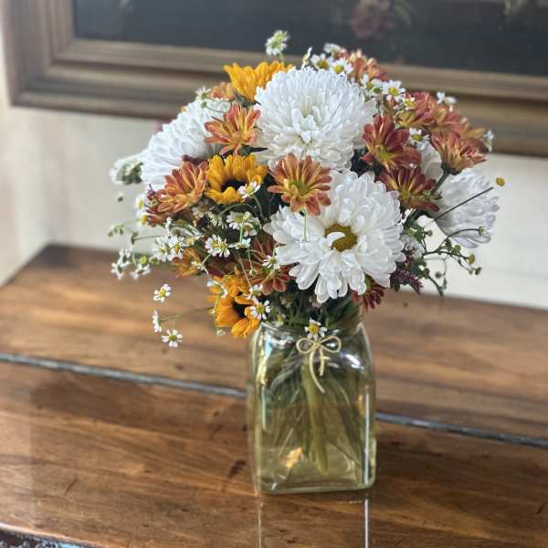 Bouquet of white and orange chrysanthemums in a glass jar