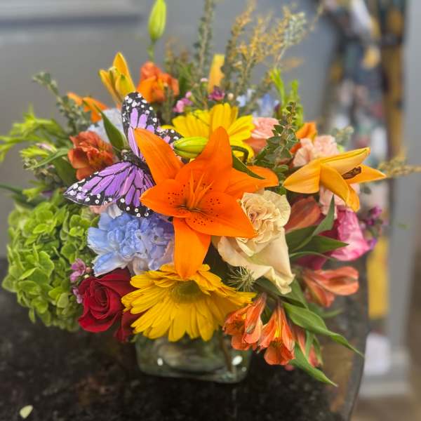 Colorful mixed bouquet with orange lilies and yellow daisies in a glass vase