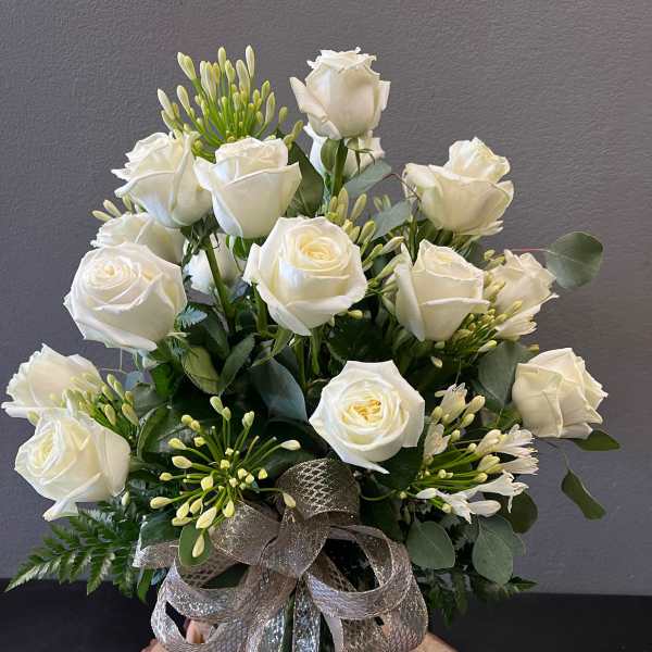 Medium vase arrangement of white roses with buds and a large silver ribbon bow.