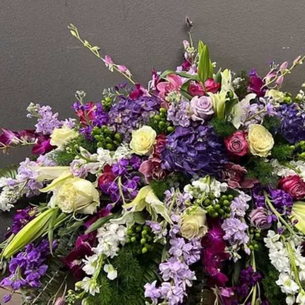 Large low spray of purple, lavender, and white roses, lilies, hydrangeas, and orchids in a dense arrangement