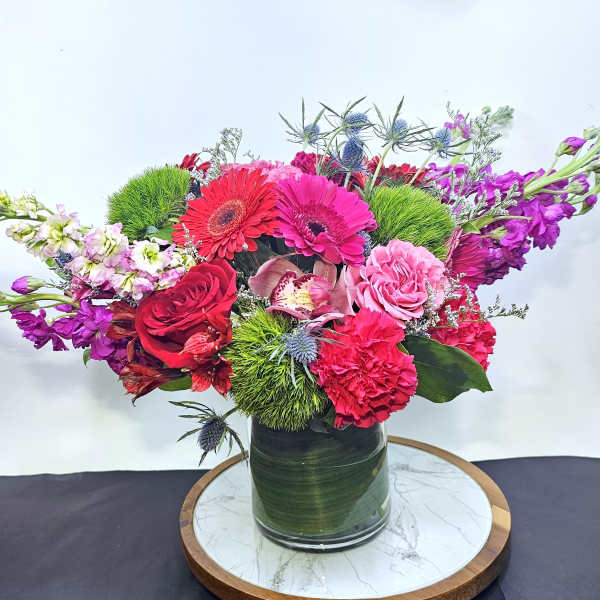 Bright mixed bouquet in a glass vase with pink, red, and purple blooms