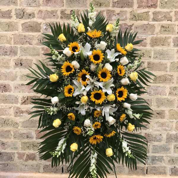 Standing floral spray with sunflowers, yellow roses, and white lilies