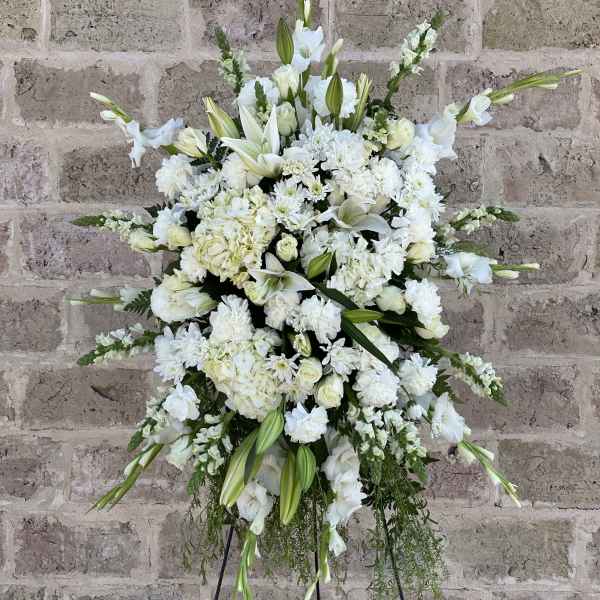 Large white funeral spray with lilies and roses on a stand