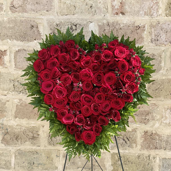 Heart-shaped red rose arrangement on a stand