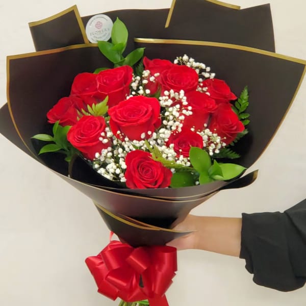Bouquet of red roses with baby's breath in dark wrapping and a red ribbon
