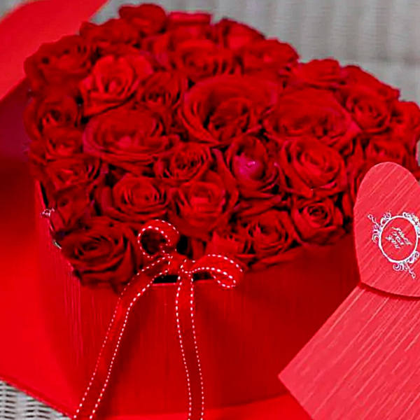 Heart-shaped box filled with red roses and tied with a red ribbon