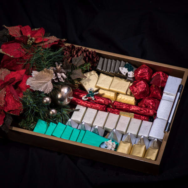 Tray of assorted wrapped chocolates with red poinsettias and holiday decorations