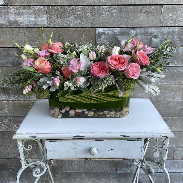Pink and peach roses arranged in a rectangular glass vase