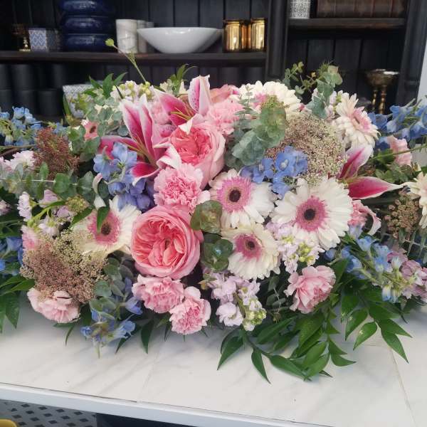 Large pastel floral arrangement with pink and white blooms and blue accents